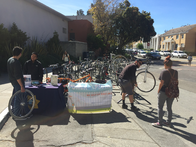 Nolen Brown, fixing bike at right, sets up an outreach table for Power to the Pedal on the S.F. State campus. Photo by Nick Kordesch.