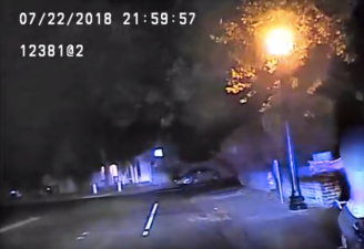 Teen on bike (lower right of image) signals to police just before getting pulled over. Screengrab from police dash-cam footage.