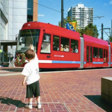 A small boy waves to a light rail train