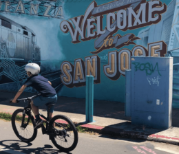 Boy rides bike past mural in San Jose
