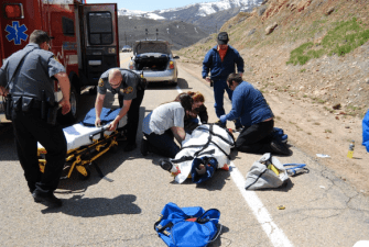 EMTs on the side of a road work to put traffic crash victim on a gurney